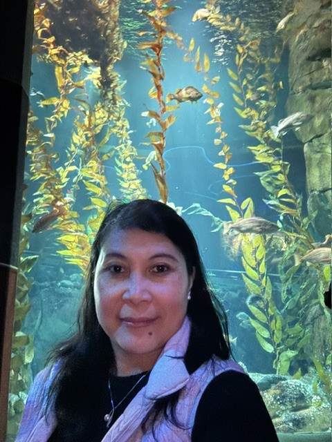 Joriza Apuada in front of an aquarium with kelp and fish
