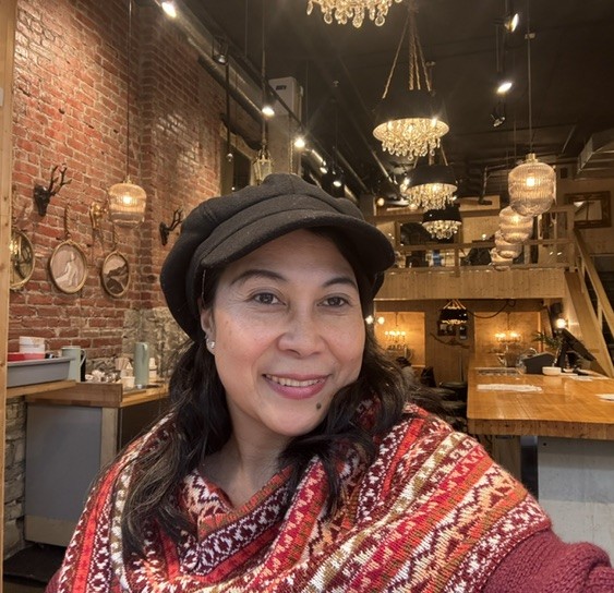 Joriza Apuada smiling in a cap and patterned scarf
